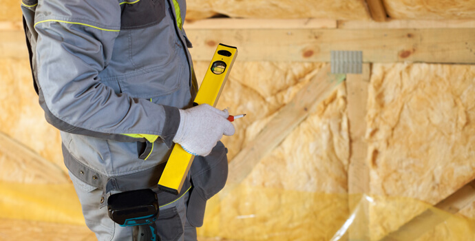 property maintenance worker installing insulation in an attic